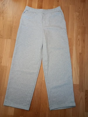 Grå mjukisbyxor från Zara - Snygga och bekväma grå mjukisbyxor från Zara med rak passform och resår i midjan. Perfekta för chill dagar hemma eller när du vill ha en avslappnad stil. Tillverkade i mjukt material som känns skönt mot huden.