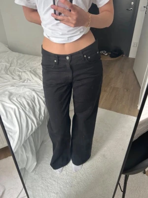 Svarta raka jeans med hög midja - Säljer ett par svarta jeans med rak passform och hög midja. Jeansen har klassisk femficksdesign och stängs med knapp och dragkedja. Perfekta för en avslappnad och trendig stil. Materialet är denim i bomull. Uppsprättade på botten därav priset.