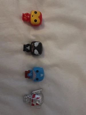 Fyra Marvel mini-figurer 50kr st - Säljer fyra små Marvel-inspirerade samlarfigurer i plast. Figurerna föreställer Iron Man, Venom, Captain America och Ant-Man. De är färgglada och har stora huvuden i klassisk Funko Pop-stil. Perfekta för dig som gillar superhjältar och vill ha coola prylar till hyllan. De sälj var för sig och INTE i pack