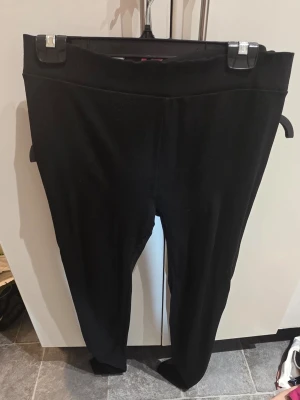 Svarta leggings med hög midja - Svarta leggings med hög midja och stretchigt material. Klassisk modell utan synliga detaljer eller fickor, perfekt för en enkel och stilren look. Bekväma och lätta att matcha med olika outfits.