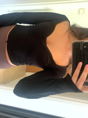 Svart topp från Bubbleroom - Trendig svart topp från Bubbleroom i stretchigt material. Toppen har lång ärm och en tight passform. Perfekt att styla med höga jeans eller kjol för en snygg look.