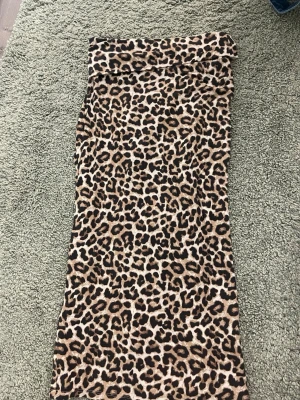 Leopardmönstrad långkjol med slits - Cool långkjol med leopardmönster i bruna och svarta toner. Kjolen har en snygg slits bak som ger extra edge till outfiten. Perfekt för dig som vill sticka ut och gillar djurmönster.