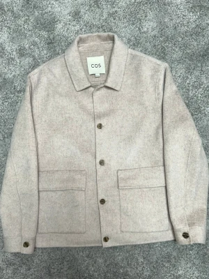 Beige overshirt från COS - Stilren overshirt i ull från COS. Använd fåtal gånger och i väldigt fint skick. Skick: 9/10 Pris kan diskuteras 📦 Skickas eller möts upp