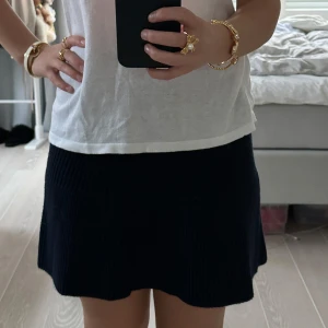 Marinblå ribbad kjol ZARA - Säljer en superfin marinblå ribbad kjol som är perfekt för både vardag och fest. Kjolen har en skön passform och är gjord i ett mjukt material som faller snyggt. Den är enkel att matcha med olika toppar och accessoarer. Perfekt för höst och vår! Märket är zara och storlek S.