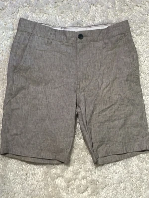 Beige shorts från Jack&Jones - Säljer ett par stilrena beige shorts från Jack and Jones De har klassisk passform med fickor fram och bak, bälteshällor och stängs med knapp och dragkedja. Materialet är lätt och passar perfekt till sommaren. Enkla att matcha med t-shirt eller skjorta.