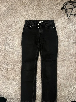 Svarta raka jeans från 157 - Svarta jeans med rak passform från 157. Klassisk femficksmodell med knappgylf och bälteshällor. Jeansen har en stilren look och är tillverkade i denim. Perfekta för en avslappnad och trendig stil.