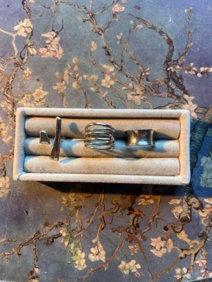 Tre silvriga statementringar - Säljer ett set med tre silvriga ringar i olika unika designer. En ring har en modern korsad form, en är spiralformad och en har en bred, slät yta. Perfekta accessoarer för att lyfta din stil med en cool och trendig touch.