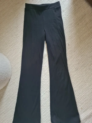 Svarta ribbade leggings från H&M - Svarta leggings från H&M med ribbad struktur ,resår i midjan och utsvängda ben. Perfekta för en avslappnad och trendig look.