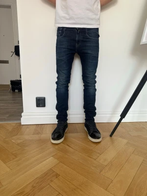 Mörkblå slim fit jeans från repaly  - Säljer ett par mörkblå slim fit jeans från repaly med klassiska fem fickor och snygga kontrastsömmar. Jeansen har en bra passform och är tillverkade i stretchigt denim för extra komfort. Perfekta för en stilren och modern look. De klasiska detaljerna på fickorna för dig som vill ha de lilla extra. Jeansens model repaly ambass, nypris 1799
