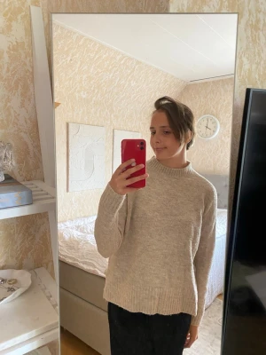 Beige stickad tröja  - Beige stickad tröja som går upp lite i halsen och även har som en slits på sidorna. Lite nopprig, från Vero Moda