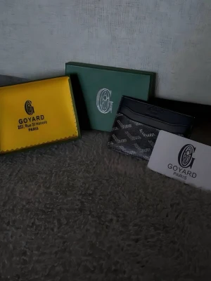 Svart plånbok - Snygg svart plånbok med klassiskt mönster i vitt och grått. Tillverkad i exklusivt läder och har flera fack för kort. Kommer med originalförpackning och äkthetskort. Perfekt accessoar för dig som gillar stilrena detaljer.