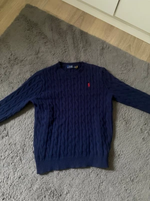Mörkblå kabelstickad tröja Polo Ralph Lauren - Säljer en Ralph louren tröja DEN ÄR STORLEK M MEN SITTER SOM S  så den är alltså liten i storleken jag säljer den för endast 422Kr riktigt bra pris eftersom att den är ny och inga defekter eller missfärgningar! Köp snarast🙌 äkta såklart 🤩