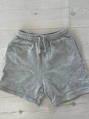 Grå mjukisshorts med snörning - Gråa mjukisshorts i bomull med elastisk midja och snörning framtill. 