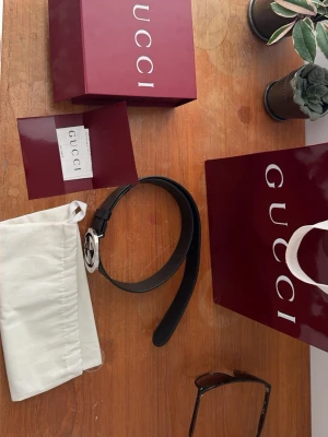 Svart skärp från Gucci med GG-spänne - Snyggt svart skärp från Gucci med GG-spännet i silver. Levereras med originalpåse och förpackning med kvitto! Köptes på Gucci i stockholm förra sommaren. Lite små repor på GG spännet och ett knapp hål är smått slitet annars hur schysst som helst inte helt säker på storlek mellan 80-100 Nypris: 4800