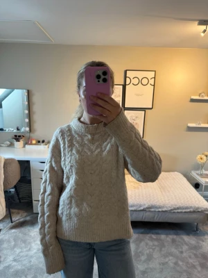 Beige kabelstickad tröja - Mysig beige kabelstickad tröja med rund hals och långa ärmar. Tröjan har ett klassiskt flätmönster både fram och bak, samt på ärmarna.❣️