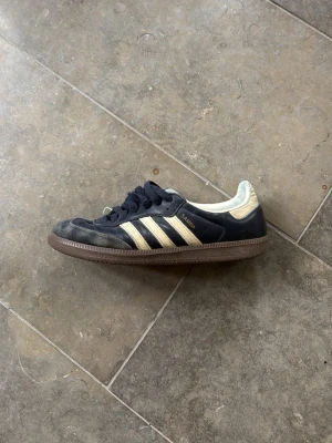 Adidas Samba svarta sneakers - Klassiska Adidas Samba sneakers i blått läder med vita detaljer. Skorna är använda men de har inga skador förutom creasing som är lätt att ta bort. Skorna är storlek 42 2/3 pris kan diskuteras vid snabb affär. Nypris runt 1200kr
