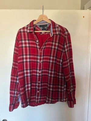 Röd rutig skjorta Tommy Hilfiger - Klassisk röd rutig skjorta från Tommy Hilfiger i vintage fit. Skjortan har långa ärmar, vit knappstängning och mjukt bomullstyg. Perfekt för en avslappnad och stilren look.  Skjortan är L men passar för M