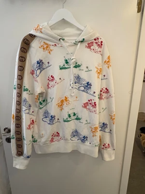 Gucci x Disney vit hoodie med tryck - Vit hoodie från Gucci x Disney med färgglada Musse Pigg-tryck i blått, grönt, rött och gult. I fint skick säljes då den blivit för stor för mig , den är äkta 