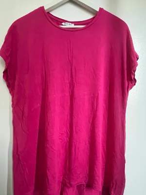Rosa oversized t-shirt - En enkel och snygg rosa t-shirt med rund hals och korta ärmar. Modellen är oversized för en avslappnad look och passar perfekt till jeans eller shorts. Tillverkad i mjuk bomull som känns skön mot huden.