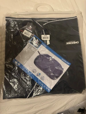 Svart ländtäcke från Onehorse - Säljer ett svart ländtäcke från OneKorse, storlek Full. Täcket är tillverkat i slitstarkt material och har vit kant runtom. Perfekt för att hålla hästen varm vid ridning eller transport. Täcket levereras i originalförpackning. Aldrig använd, storlek full. 