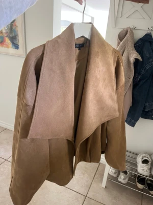 Camelbrun kappa med vattenfalls-krage - Stilren camelbrun kappa med oversized vattenfalls-krage och öppen front. Tillverkad i mjukt mockaliknande material, från Zara och använd fåtal gånger så som ny! 