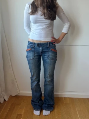 Blå bootcut jeans  - Lågmidjade jeans med coola detaljer. Storlek M, midja: 40x2 cm inneben: 84 cm