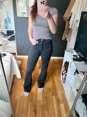 Svarta bootcut jeans - Säljer ett par svarta bootcut jeans med medelhög midja och klassiska fem fickor. Jeansen har en snygg tvätt och utsvängda ben. Otroligt sköna och knappt använda heller!