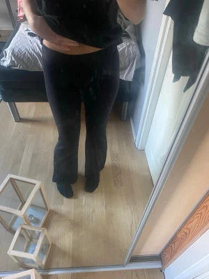 Svarta ribbade bootcut leggings - Säljer ett par svarta leggings med ribbad struktur och bootcut-modell. De har hög midja och är stretchiga för en bekväm passform. Perfekta för dig som gillar en enkel men trendig stil.