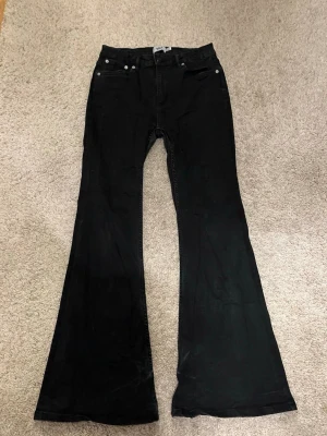 Svarta utsvängda jeans från 157 - Petite längd passar dig mellan 159-164 skulle jag gissa. Snygga svarta jeans från 157 med utsvängda ben och klassisk femficksmodell. Jeansen har hög midja och är tillverkade i ett stretchigt denimtyg som sitter bekvämt. Perfekta för dig som gillar en trendig och retro look.