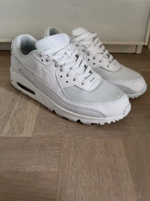 Nike Air Max 90 - Säljer ett par klassiska Nike Air Max 90 sneakers i helvitt. Skorna har en chunky sula med synlig Air-enhet, ovandel i mesh och läder samt ikoniska swoosh-loggan på sidan. Perfekta för dig som gillar stilrena och tidlösa sneakers. Skriv vid intresse!