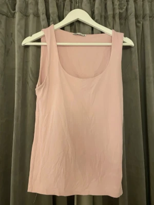 Ljusrosa linnetopp från Zara - Säljer en enkel och stilren ljusrosa linnetopp från Zara. Toppen är ärmlös med rundad urringning och har en mjuk, tunn känsla. Perfekt att matcha med jeans eller kjol för en avslappnad look.