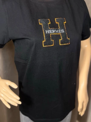 Svart  t-shirt  - . Klassisk rund hals och korta ärmar. Perfekt för dig som gillar stilrena plagg med en exklusiv touch.