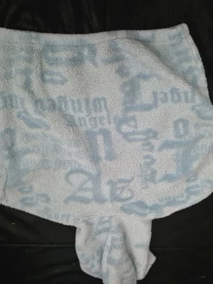 Ljusblå teddy loungewear med textmönster - Supermjuk loungewear i teddy-material med ljusblått och vitt textmönster. Plagget har en avslappnad passform och dragsko i midjan för extra komfort. Perfekt för att chilla hemma i och hålla sig varm. Materialet är fluffigt och ger en cozy vibe.