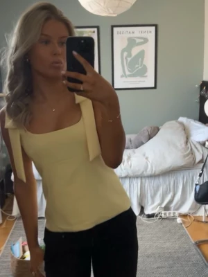 Ljusgul linnetopp med knytband - Trendig ljusgul linnetopp med breda axelband som knyts till rosetter på axlarna. Hör av er vid intresse🫶🏼