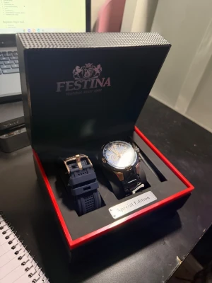 Festina Special Edition blå klocka - Säljer en Festina Special Edition klocka med blå urtavla och detaljer i silver och guld. Medföljer extra blått armband och verktyg för byte. Klockan har sportig design med kronograf och robust metallarmband. Perfekt för dig som gillar stilrena accessoarer.
