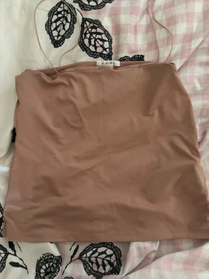Beige topp från Amisu - Säljer en beige axelbandslös topp från Amisu. Toppen har en enkel och stilren design med smala axelband och är tillverkad i ett mjukt, stretchigt material som sitter snyggt på kroppen. Perfekt till sommaren!