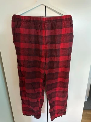Rödrutiga pyjamasbyxor Calvin Klein - Säljer ett par rödrutiga pyjamasbyxor från Calvin Klein med elastisk midja. Byxorna har ett klassiskt rutmönster i rött samt en liten broderad CK-logga på benet. Perfekta för chillkvällar hemma. Det finns ett ytterst litet ”slitage” längst ned på höger ben se bild), men inget man lägger märke på!