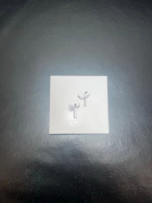 Apple AirPods Pro 2 trådlösa hörlurar - Säljer ett par Apple AirPods Pro 2, trådlösa in-ear hörlurar i vit färg. Kommer i originalförpackning med laddningsetui. Snygg och kompakt design med korta stjälkar och silikonproppar för bra passform. Perfekta för musik, samtal och träning.