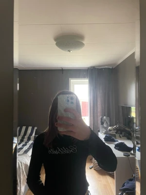 Svart ribbad långärmad topp - Säljer en svart ribbad långärmad topp med texten 'Celebrate' i glittriga stenar framtill. Toppen har en croppad passform och är perfekt för dig som gillar trendiga detaljer. Materialet känns mjukt och stretchigt, troligen polyester eller bomull.