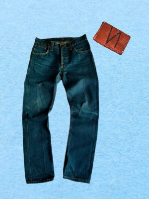 Mörkblå jeans från Nudie Jeans - Snygga mörkblå jeans från Nudie Jeans med klassisk femficksmodell och raka ben. Jeansen har kontrastsömmar och är tillverkade i slitstark denim av bomull. Perfekta för en avslappnad och trendig look.