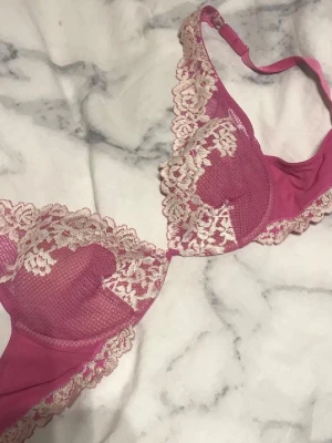 Rosa spets-bh med blommig brodyr - Säljer en snygg rosa bh med beige spetsdetaljer och blommig brodyr. Bh:n har bygel och justerbara axelband. Materialet är en kombination av mesh och spets som ger en romantisk och feminin look. Den är från intimissimi och säljs inte längre🥰
