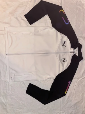 Neymar träningsjacka Puma - Säljer en snygg Neymar träningsjacka från Puma med svarta ärmar och färgglada detaljer på armarna. Jackan har hel dragkedja, två sidofickor och Puma-logga på bröstet. Perfekt för träning eller sportiga dagar.