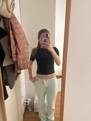 Svart croppad topp från H&M Move - Svart, tight och croppad topp från H&M Move med korta ärmar. Perfekt för en sportig look eller att styla till vardags. Tillverkad i ett stretchigt material som sitter snyggt och bekvämt.