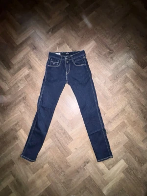 Mörkblå jeans från Replay - Säljer ett par mörkblå jeans från Replay med klassiska kontrastsömmar och raka ben. Jeansen har två fram fickor och detaljerade bakfickor. Size: 29 på midjan och längden är också 29. Mer jeans finns på min profil 