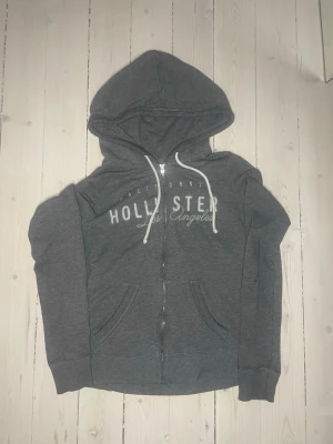 Hollister hoodie grå - En hollister hoodie i grå som är i väldigt fint skick förutom nått litet hål på ärmen (ses på sista bilden) skriv gärna vid frågor storlek S :) ❄️☃️