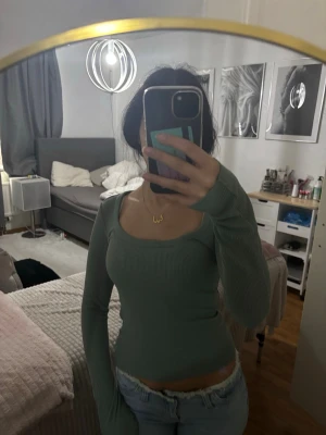Ljusgrön ribbad långärmad topp - Trendig ljusgrön ribbad topp med lång ärm och fyrkantig ringning. Sitter tight och har en croppad passform som passar perfekt till jeans eller kjol. Materialet känns mjukt och stretchigt, vilket gör den bekväm att bära hela dagen.