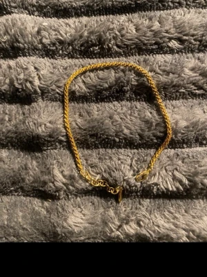 Tunt guldarmband med kedjelänk - Snyggt och enkelt armband i guldfärgad metall med tunn kedjelänk. Armbandet har ett klassiskt karbinlås och passar perfekt för dig som gillar stilrena accessoarer. Ingen synlig märkning på armbandet.