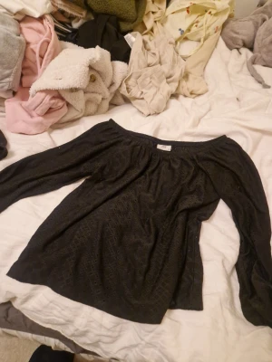 Svart offshoulder topp från JDY - Snygg svart offshoulder topp från JDY i storlek XS. Toppen har lång ärm och ett diskret prickigt mönster i tyget som ger en cool touch. Perfekt att styla med jeans eller kjol för en trendig look. Ofsholder