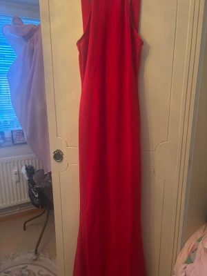 Röd långklänning från Missguided - Snygg röd långklänning från Missguided med ärmlös design och djup urringning i ryggen. Klänningen har en rak och elegant siluett som ger ett stilrent intryck. Perfekt för dig som vill sticka ut med en färgstark look.