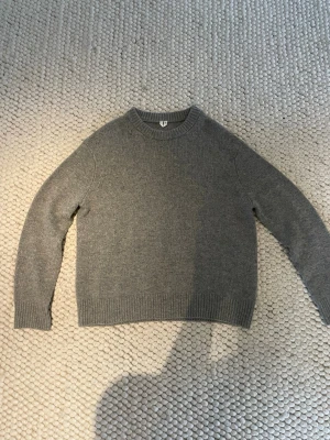 Grå stickad tröja från ARKET - En stilren grå stickad tröja från Arket som är oanvänd med rund halsringning och ribbade muddar vid ärmslut och nederkant. 